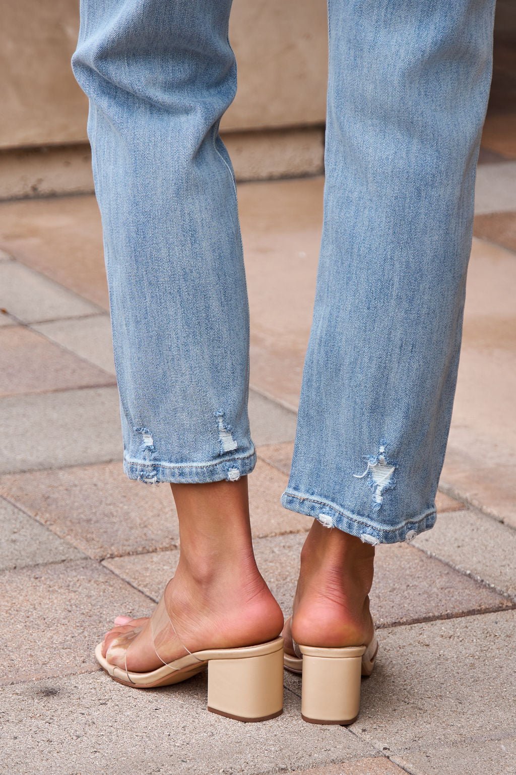 Person wearing Distressed Slim Straight Leg Jeans - Medium Wash-FINAL SALE and nude chunky heeled sandals, standing on tiled pavement.