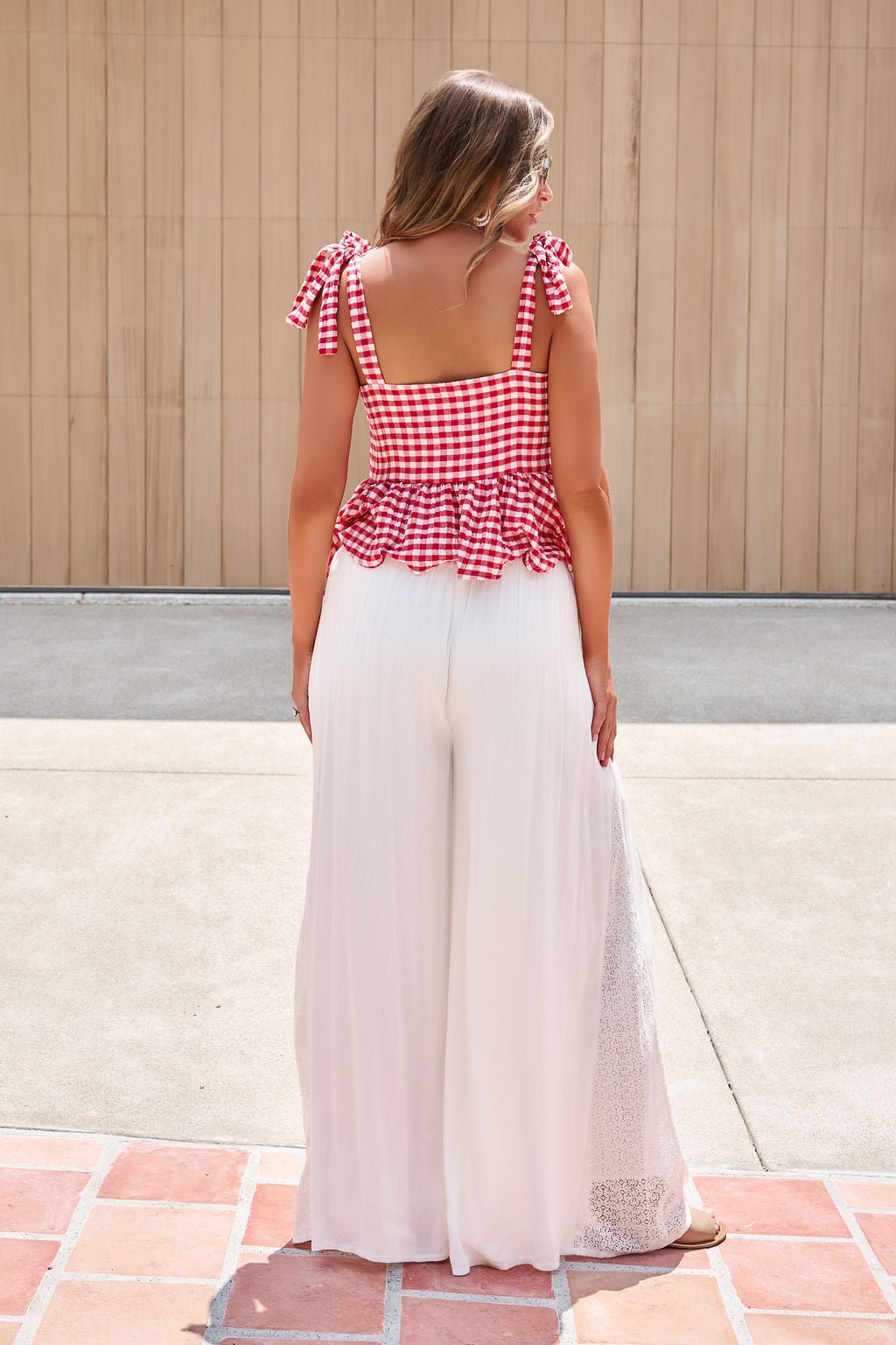 Woman outdoors in a red gingham top and Elan Flowy Wide Leg Pants - Ivory, standing against a wooden wall.