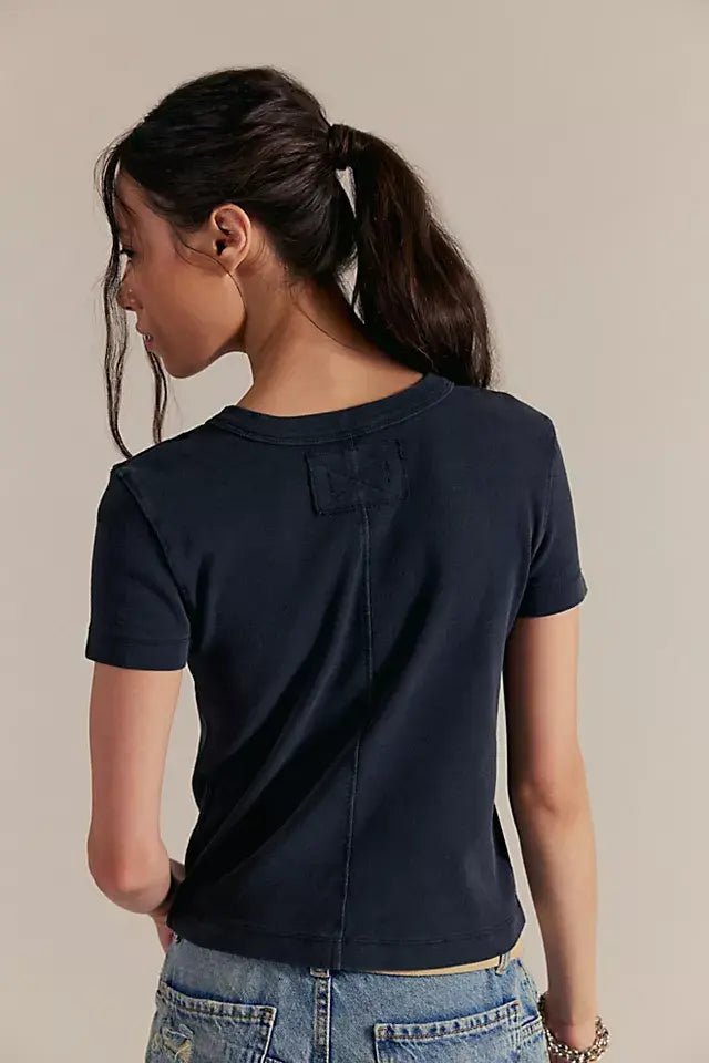 Woman with long dark ponytail in a fitted Free People Atlas Crew Tee in Charcoal and light blue jeans, seen from the back.