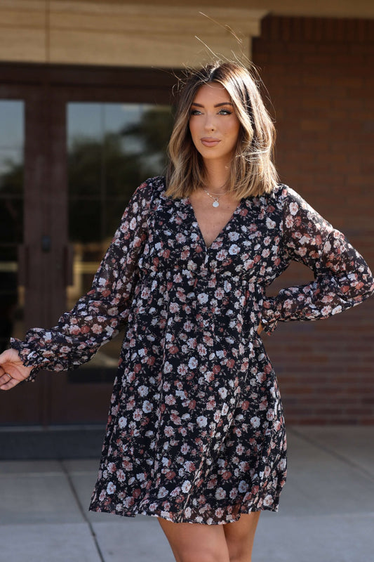 Woman in the Thalia Black Floral Print Mini Dress stands outdoors by a building. Magnolia exclusive. FINAL SALE.