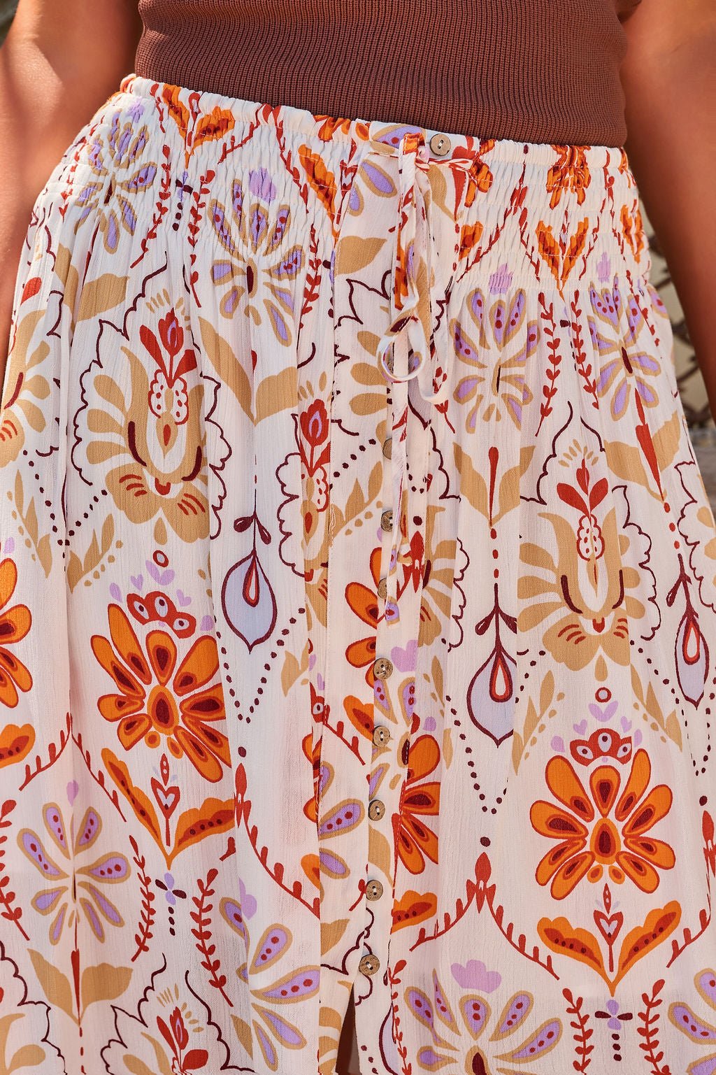 Close-up of the Tropical Treasure Print Maxi Skirt in cream, featuring a floral pattern, paired with a brown top.