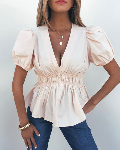Woman wears the Blush Puff Sleeve Peplum Top - FINAL SALE with blue jeans, standing against a plain white background.