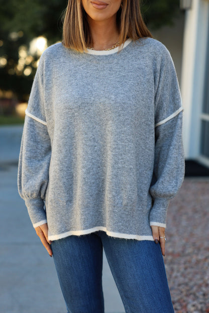 Woman wears the Grey Contrast Detail Pullover Sweater with blue jeans outdoors—an ideal pick for any fall wardrobe. Face partly out of frame.