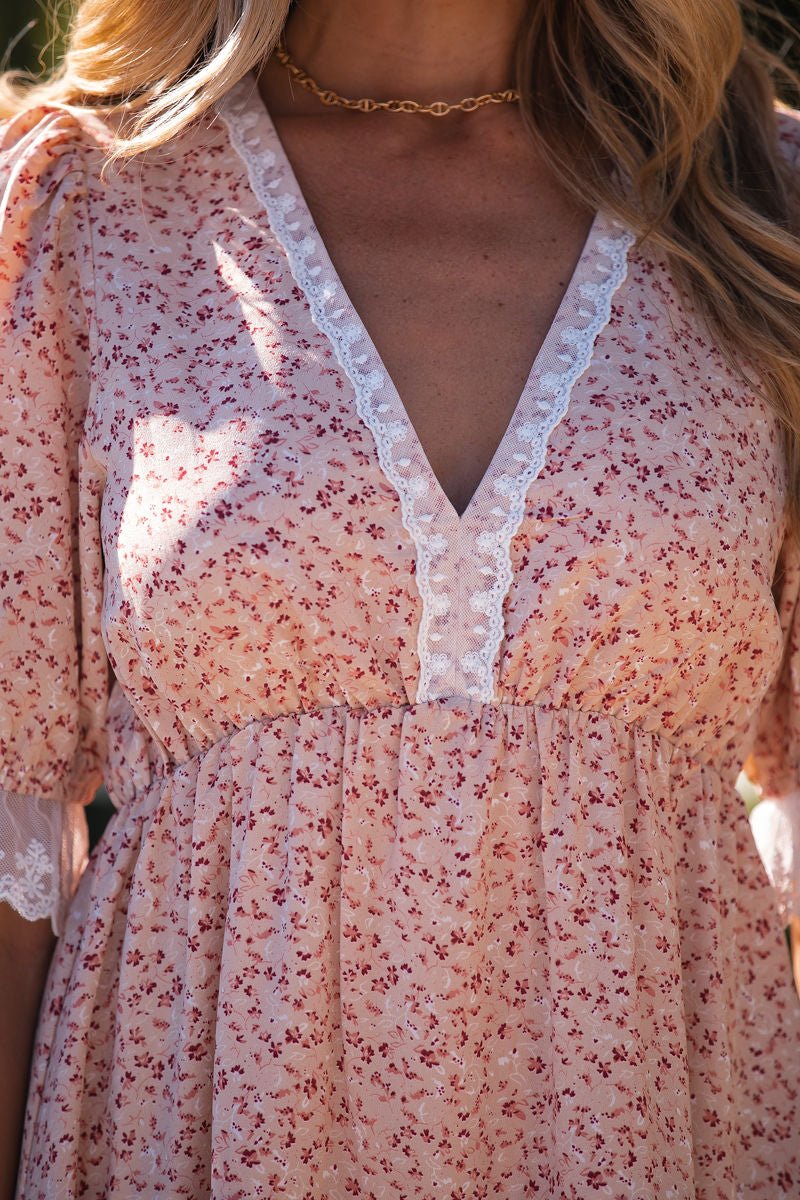 Woman wearing the Beige Floral Lace Tiered Mini Dress - FINAL SALE, photographed from shoulders to waist.