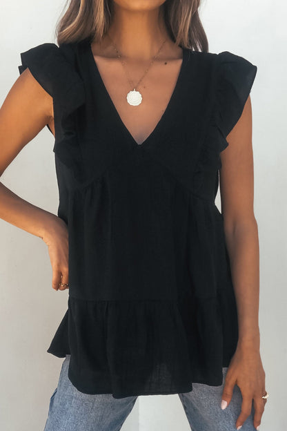Woman in Black Ruffle Sleeve Textured Top- FINAL SALE with blue jeans and round pendant necklace against a plain background.