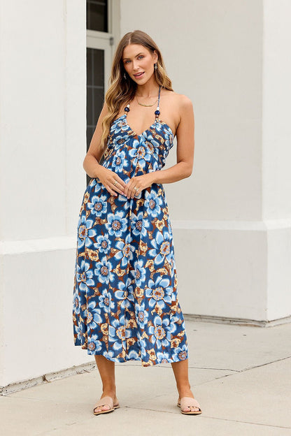 Woman wears the Catalina Halter Midi Dress in navy, smiling outside near a white building.