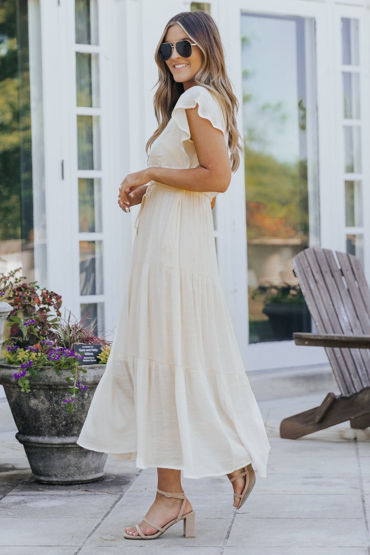 Woman in the Celine Crochet Lace Tiered Boho Midi Dress stands on a patio, smiling in sandals, sunglasses, and loose hair.