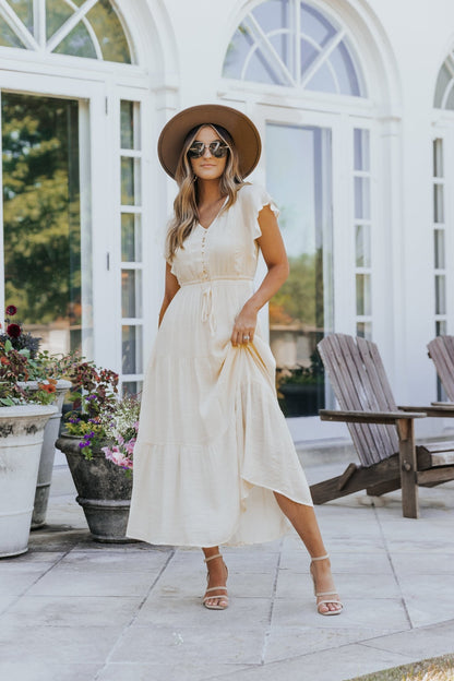 Woman in the Celine Crochet Lace Tiered Boho Midi Dress stands on a patio near potted flowers, wearing a hat and sunglasses.