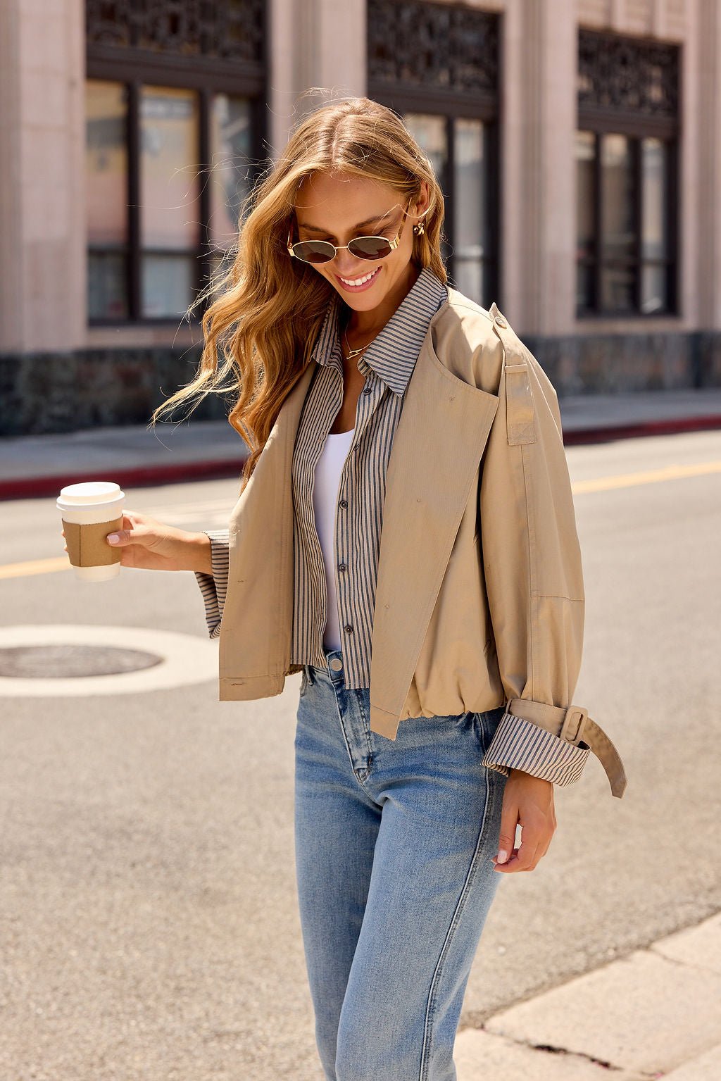 Woman in sunglasses styles the Contrast Striped Shirt Jacket - Camel as a perfect transitional layer with jeans and coffee in hand.