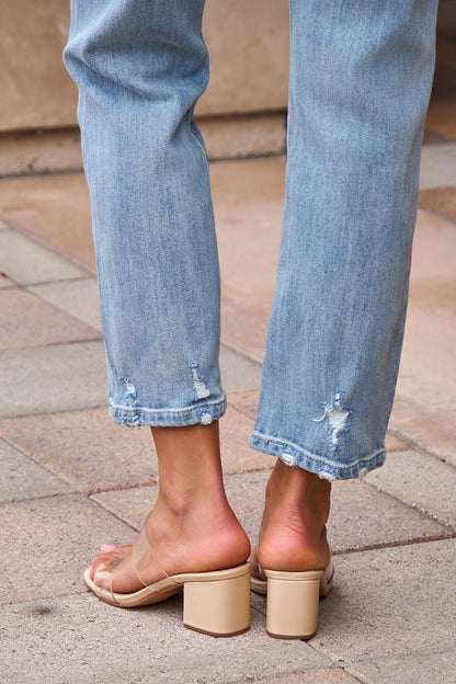 Person wearing Distressed Slim Straight Leg Jeans - Medium Wash-FINAL SALE and nude chunky heeled sandals, standing on tiled pavement.