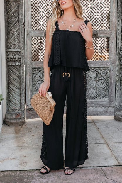 Woman wearing ELAN Black Lace Trim Wide Leg Pants, paired with a clutch and layered jewelry by ornate doors.