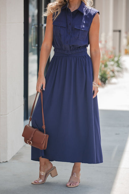 Woman in the Elan Navy Collared Button Down Top, styled with clear heeled sandals and a brown shoulder bag outdoors.
