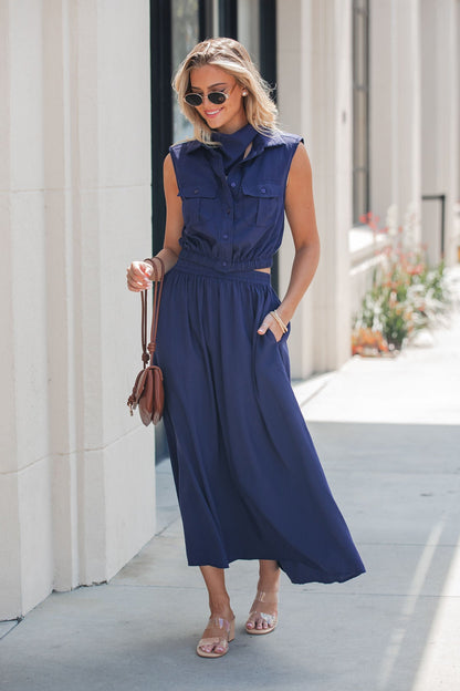 Woman in an Elan Collared Button Down Top - Navy walks on a sunny sidewalk, sunglasses and brown handbag in hand.