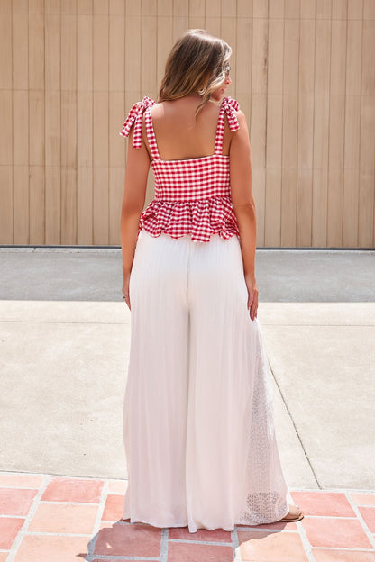 Woman outdoors in a red gingham top and Elan Flowy Wide Leg Pants - Ivory, standing against a wooden wall.