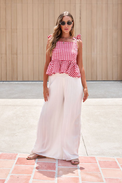 Woman in sunglasses, red gingham top, and Elan Flowy Wide Leg Pants - Ivory stands on a sunny paved area.