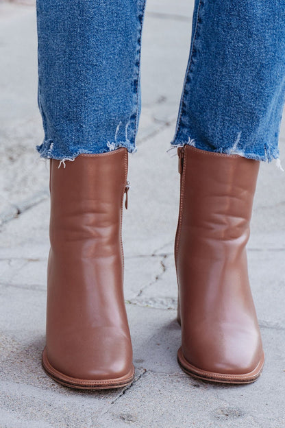 Evelyn Taupe Leather Heeled Ankle Booties paired with frayed hem blue jeans, shown from the front on a concrete surface.