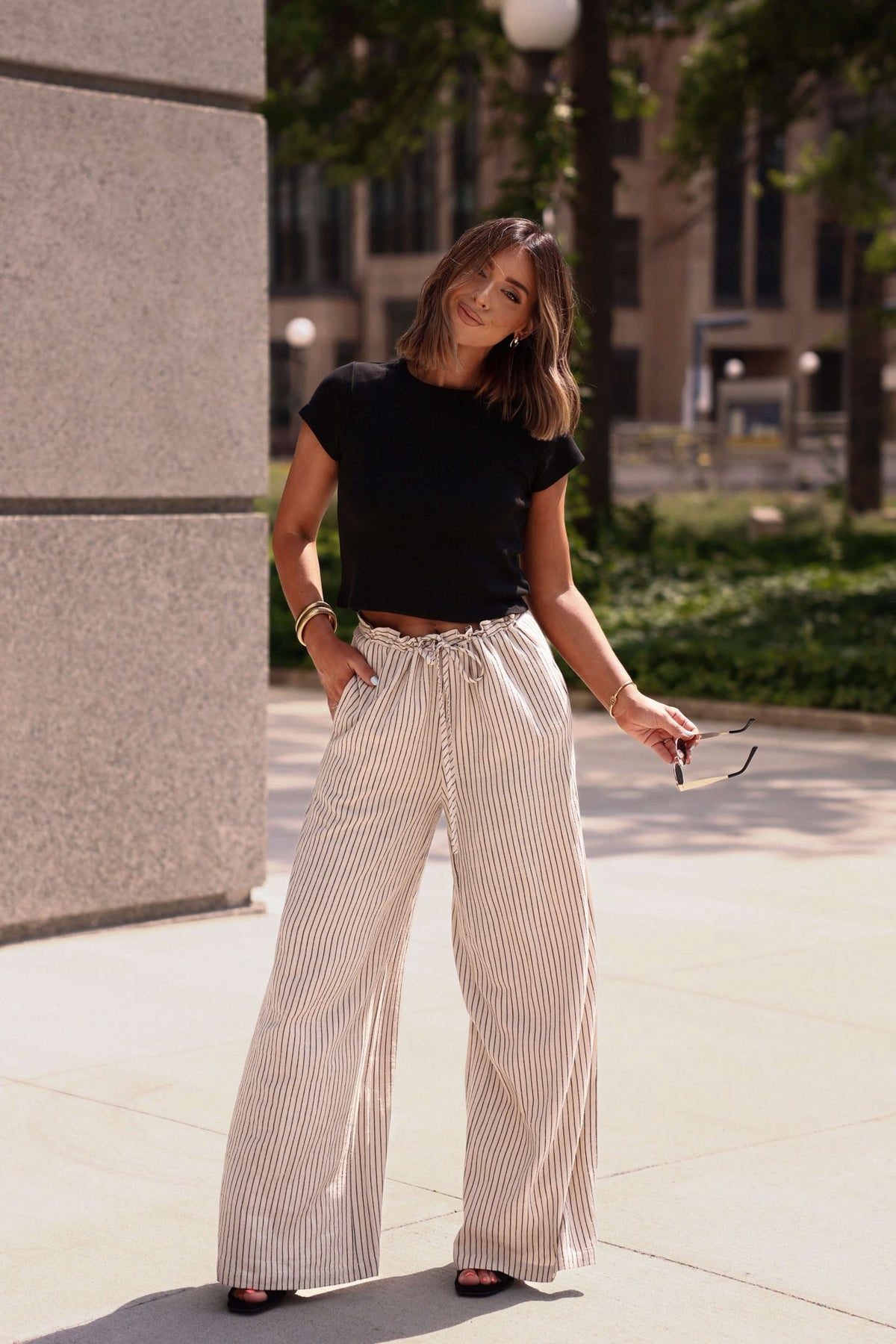 Woman in the Everyday Essential Black Tee-FINAL SALE enjoys 100% cotton softness and a comfortable fit outside.