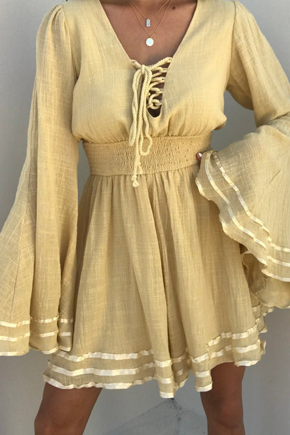 Woman in a Golden Hour Bell Sleeve Romper - FINAL SALE, featuring flared sleeves, lace-up front, smocked waist, and white trim.