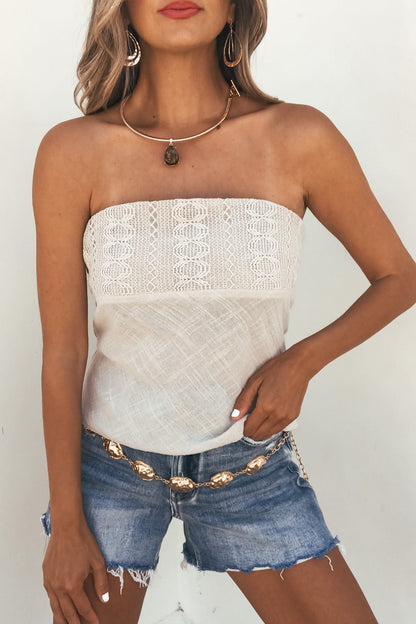 Woman in Isla Natural Lace Tube Top - FINAL SALE, denim shorts, gold jewelry, and chain belt stands against a white background.