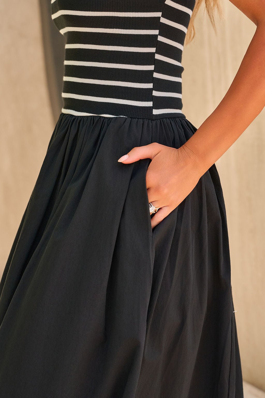 Woman wearing the Monaco Strapless Midi Dress in black, hand in pocket.