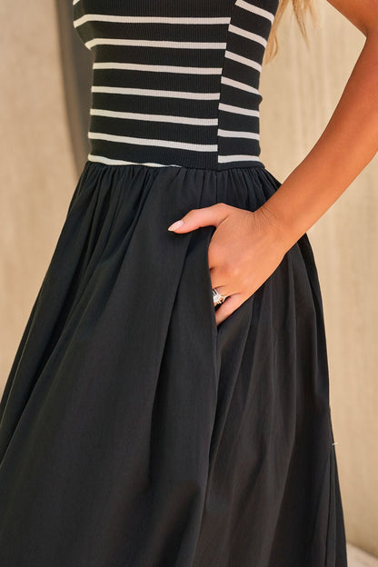 Woman wearing the Monaco Strapless Midi Dress in black, hand in pocket.