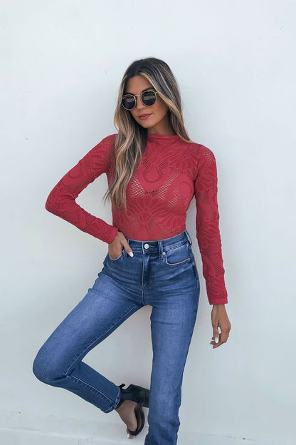 Woman in sunglasses models the Red Mock Neck Fishnet Top with high-waisted jeans, standing by a plain white wall.