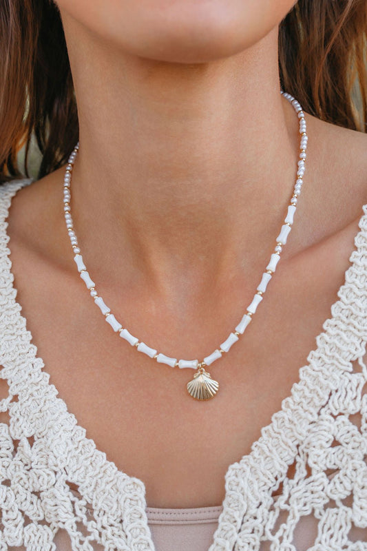 A woman wears the Seabreeze Pearl Shell Pendant Necklace - FINAL SALE with a cream crochet top.