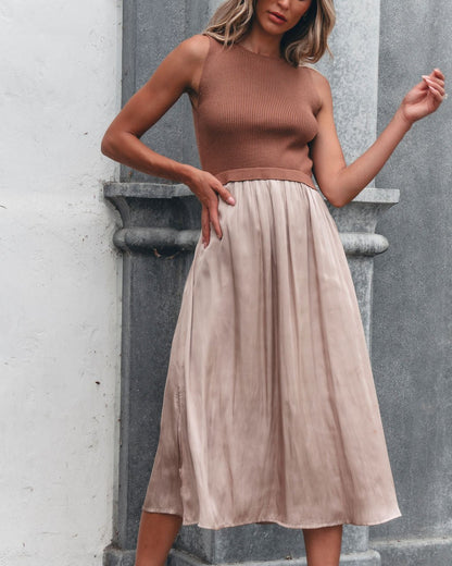 Woman in the Sleeveless Half Sweater and Satin Skirt Midi Dress - Mocha, standing by a stone wall.