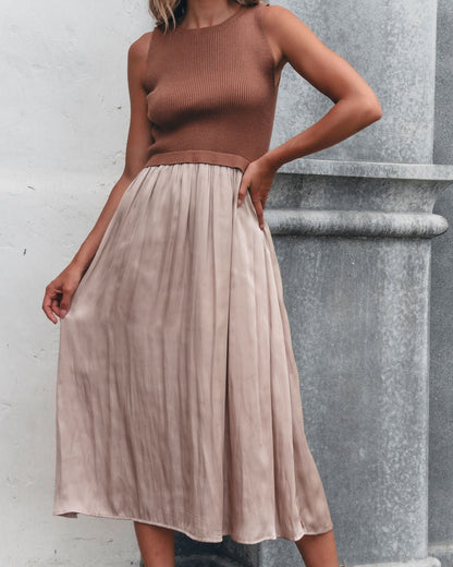 Woman in a mocha Sleeveless Half Sweater and Satin Skirt Midi Dress, standing by a stone column.