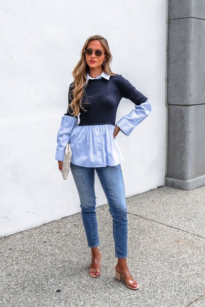 Woman in sunglasses, Steve Madden Lenny Top - Navy, jeans, and heels stands outdoors holding a beige clutch against a white wall.