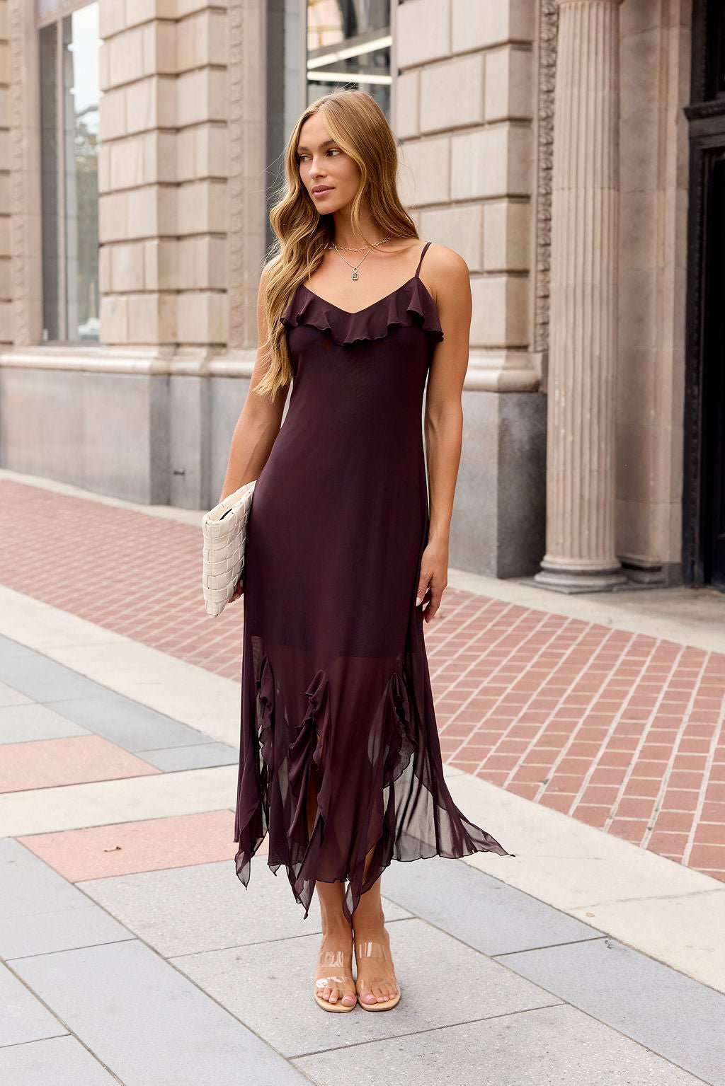Woman in the Steve Madden Mariane Midi Dress - Brow stands on a city sidewalk, holding a woven clutch.