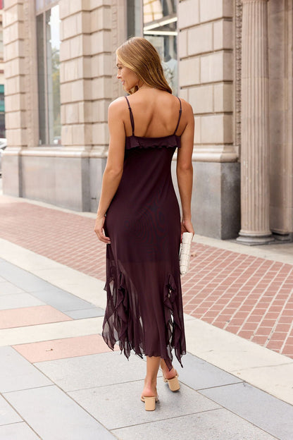 Woman in a sleeveless Steve Madden Mariane Midi Dress - Brow, ruffled trim, with heels and a white clutch walks on a city sidewalk.