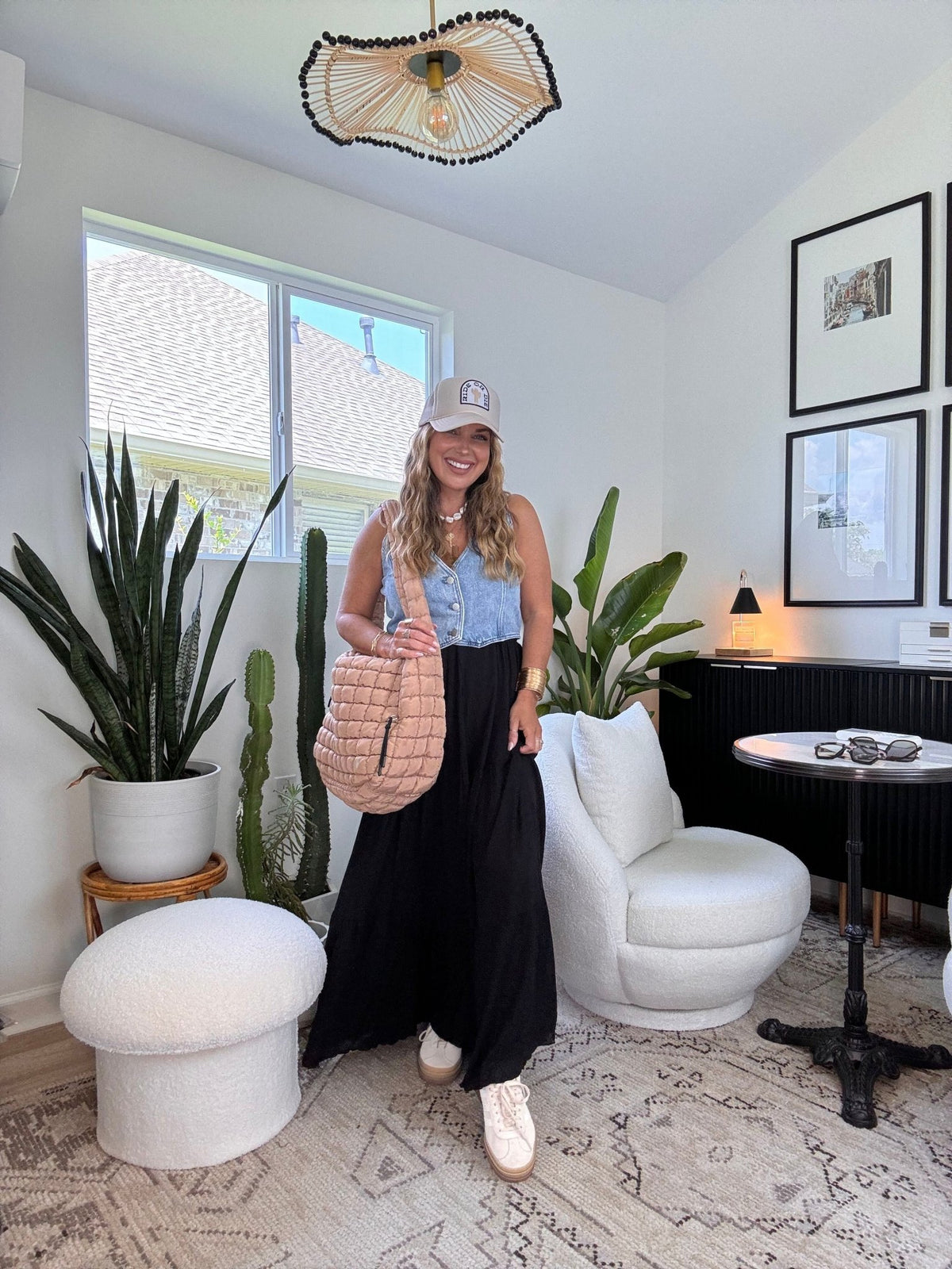 Woman in a chic living room wearing the Sunrise Short Sleeve Top & Maxi Skirt Black Set, smiling at the camera.