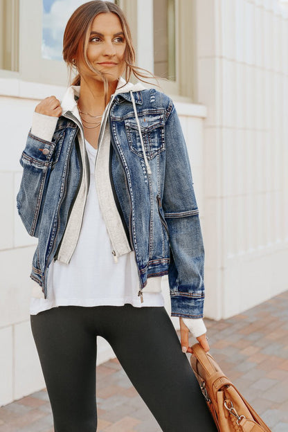 Woman in a Denim Jacket with Hoodie: Medium Wash, white shirt, black leggings, holding a brown bag on a paved sidewalk.