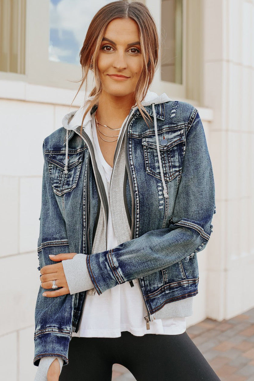 Woman in a Denim Jacket with Hoodie: Medium Wash over a white top and black leggings, standing outside and smiling softly.