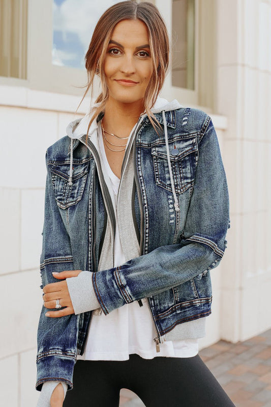 Woman in a Denim Jacket with Hoodie: Medium Wash over a white top and black leggings, standing outside and smiling softly.