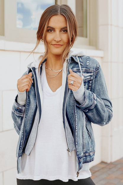 Woman with long brown hair wears Denim Jacket with Hoodie: Medium Wash over a white top, smiling outdoors at the camera.