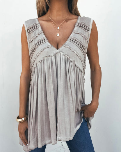 Woman in a bump-friendly Taupe V Neck Flowy Top-FINAL SALE, blue jeans, layered necklaces, and a gold bracelet.