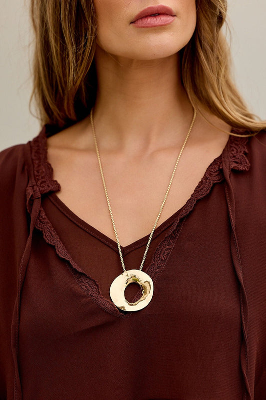 Woman in a brown blouse with lace trim, wearing The Eclipse Pendant Necklace - Gold.