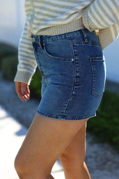 Person wearing a striped sweater and Thread and Supply Medium Wash Rowan Mid Rise Shorts - FINAL SALE outdoors on a sunny day.