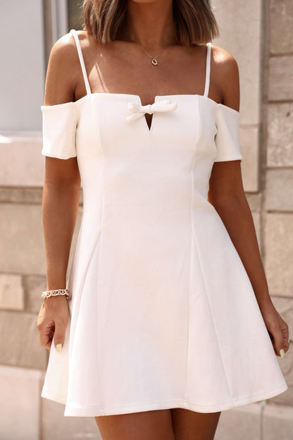 A woman stands outdoors in the White Cold Shoulder Flare Mini Dress—an elegant pick for chic bridal events.
