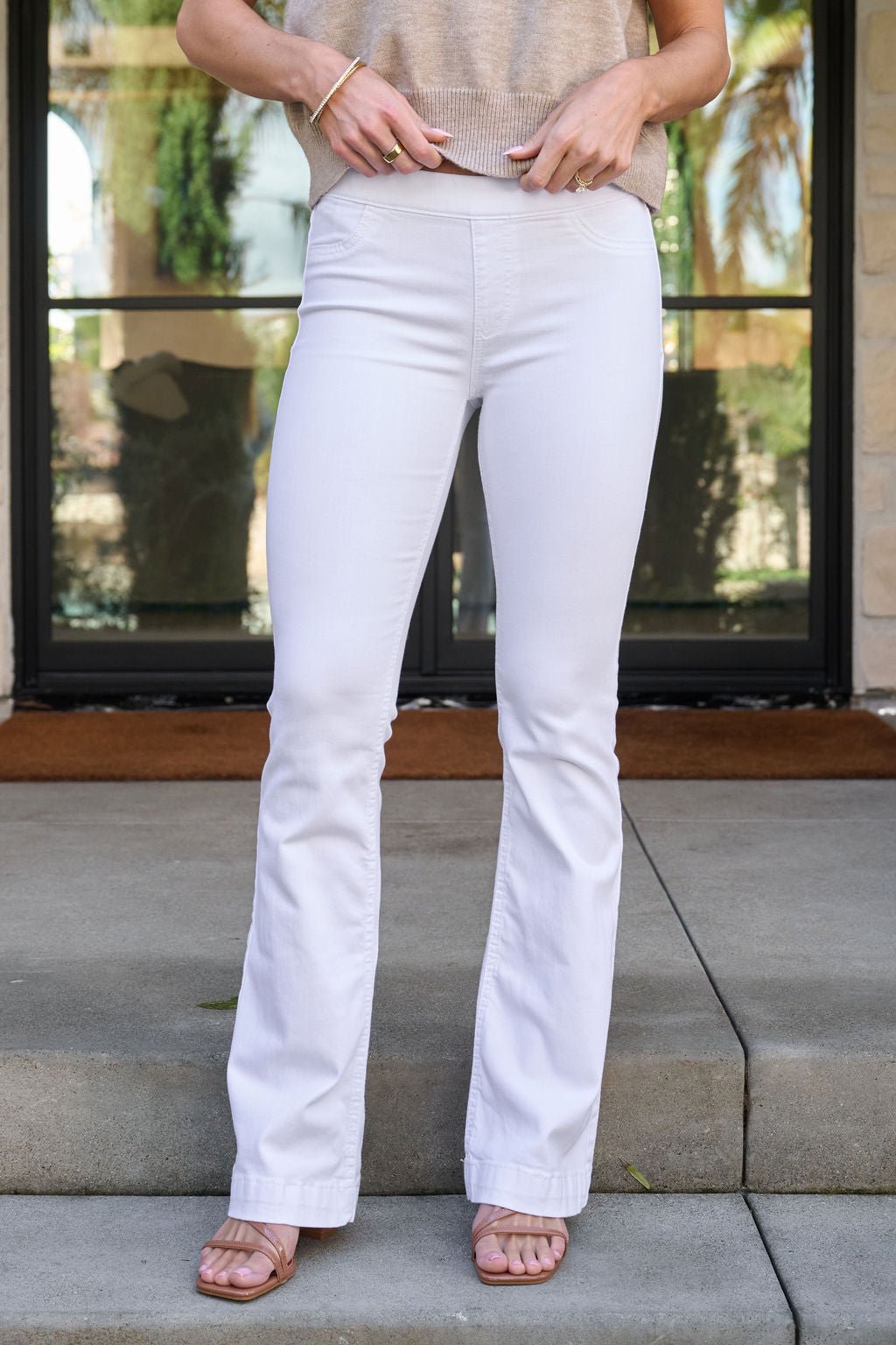 Woman on steps wears White Mid Rise Flare Pull-On Jeggings - FINAL SALE, a beige top, and sandals; face not shown.