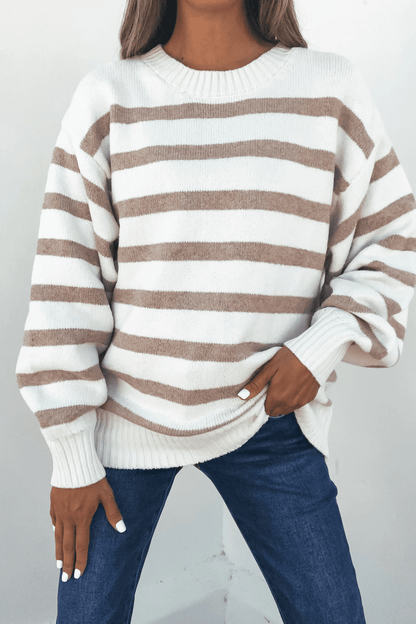 Person in a Willow Cream Stripe Ribbed Sweater and blue jeans, hand in pocket, standing against a plain light background.