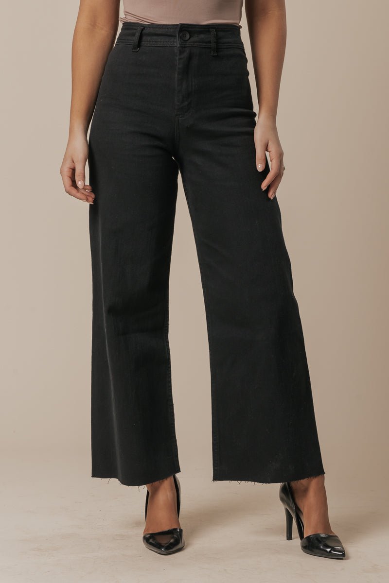 Model wears Black Straight Wide Leg Jeans with a beige top and black heels, posing against a plain background.