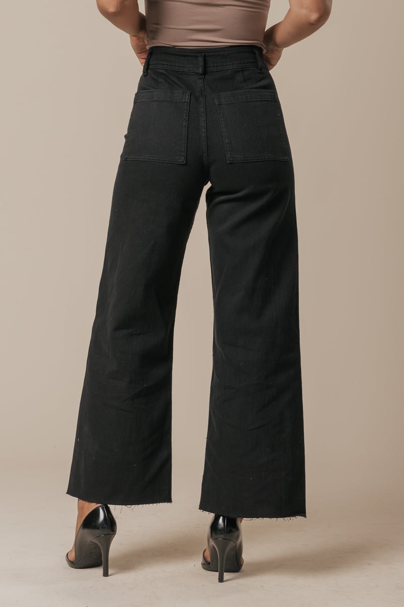Model wears Black Straight Wide Leg Jeans with black heels, pictured from the back with hands on hips against a beige background.