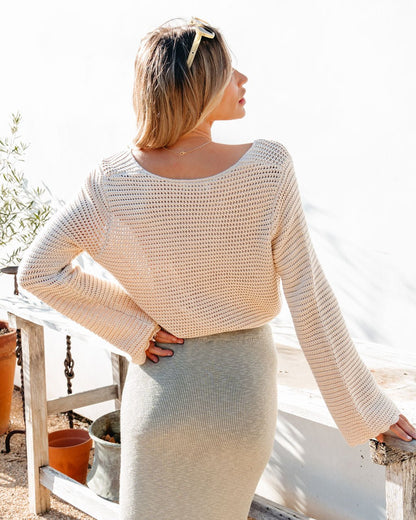 Outdoors, a woman poses by a white wall in the California Cinched Button Down Sweater—ideal for everyday style.
