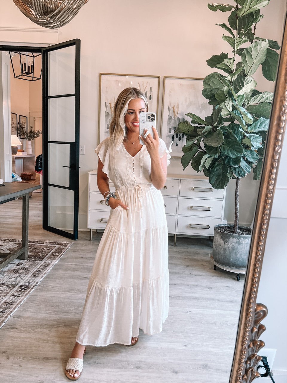 Woman in Celine Crochet Lace Tiered Boho Midi Dress takes a mirror selfie in a bright, modern room with plants and artwork.