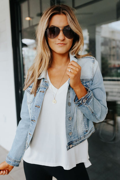 Woman wears Sweet South Faded Denim Jacket - Light Wash over a white top, showcasing effortless casual layering outdoors.